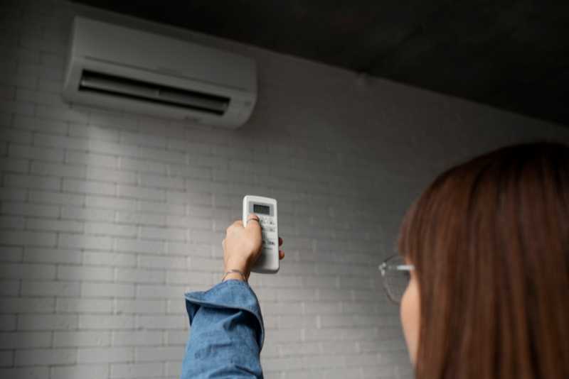 Lady using remote control to operate wall mounted air conditioner